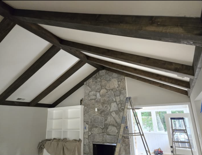 Completed dark stained rustic ceiling beams, built-in shelving, and stone fireplace by Quality Painting & Home Repairs in Dallas GA