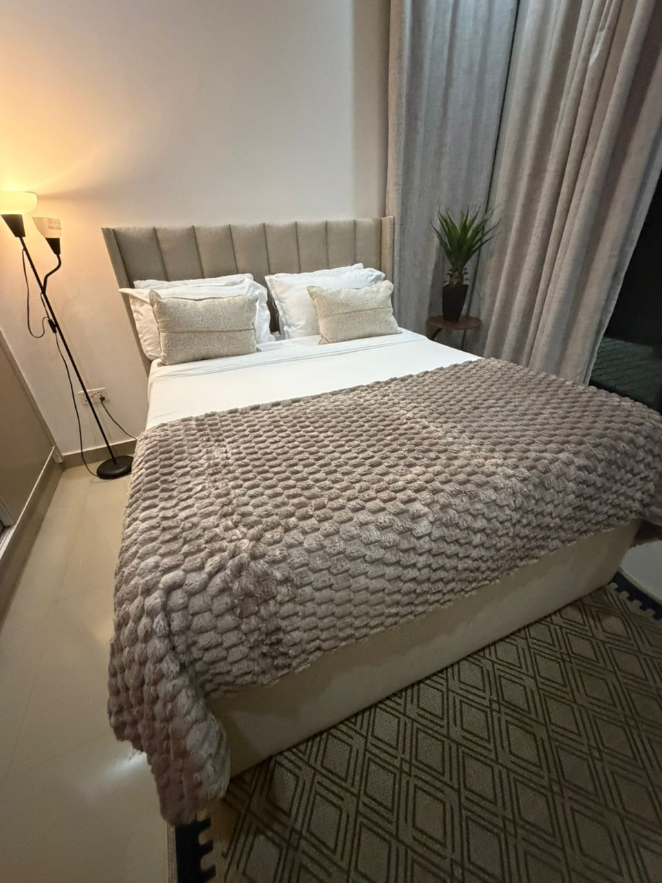 Master bedroom suite with ambient floor lamp and elegant drapes