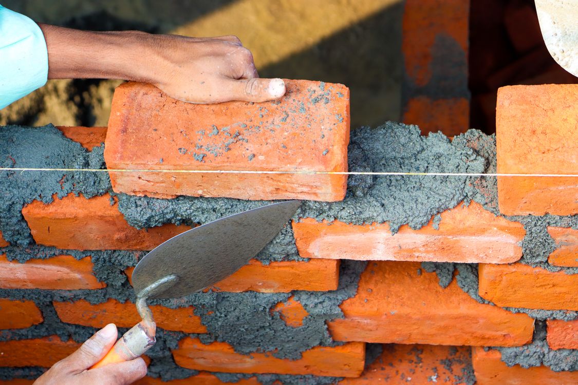 Mason placing bricks with mortar