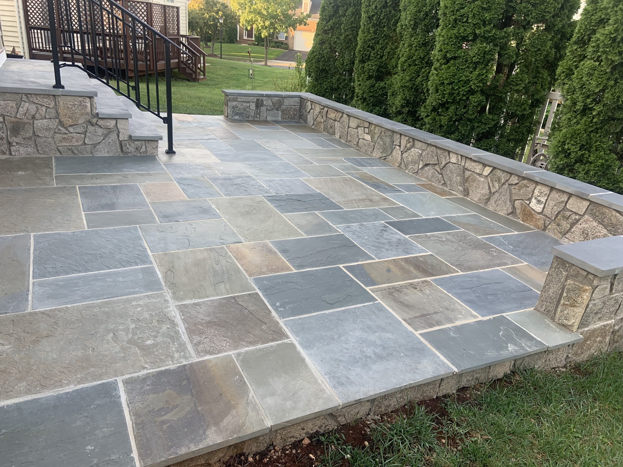 Natural stone patio with low perimeter walls and stone steps by Lionstone