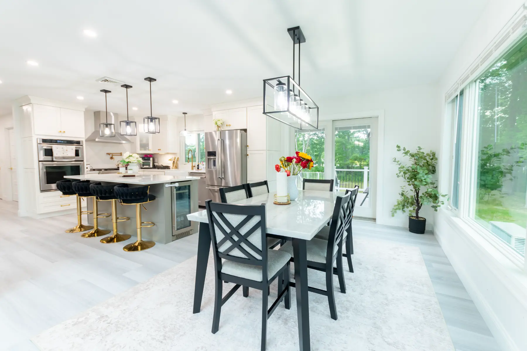 Bright, open-concept kitchen and dining room featuring a large island, modern pendant lighting, and expansive windows.