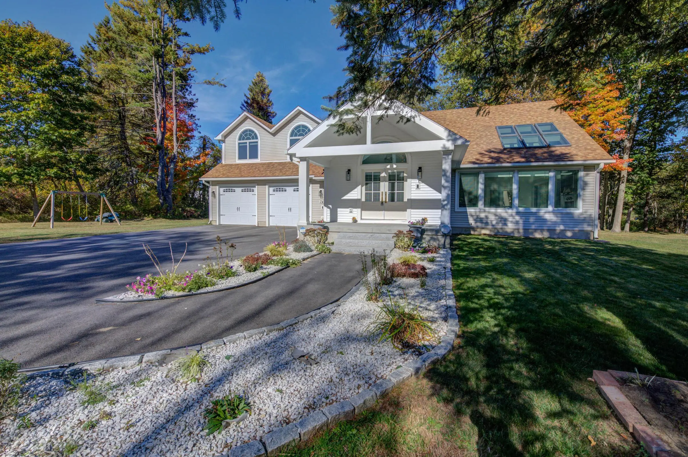 Southern Maine residential home with attached two-car garage, landscaped driveway, and mature trees.
