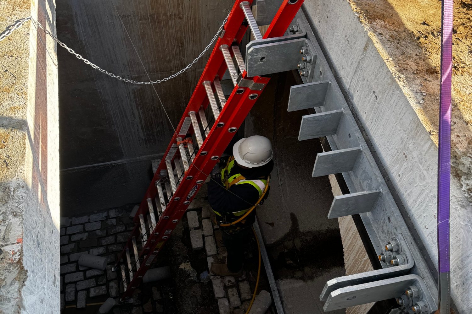 Worker in a gate slot with ladder and galvanized brackets.