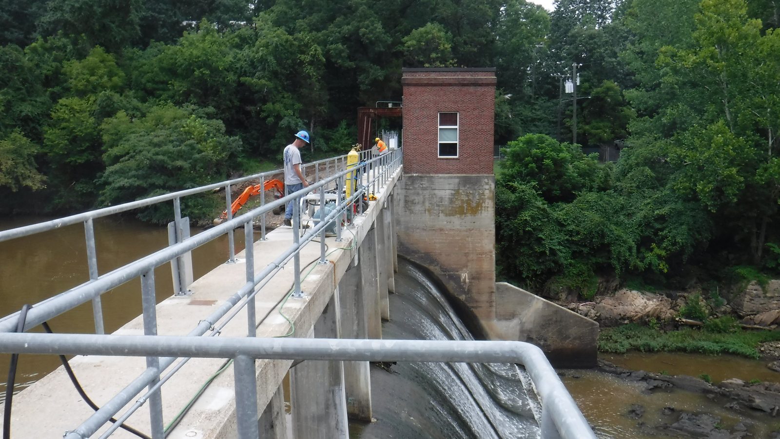 Crew working on the walkway of a small hydro dam.