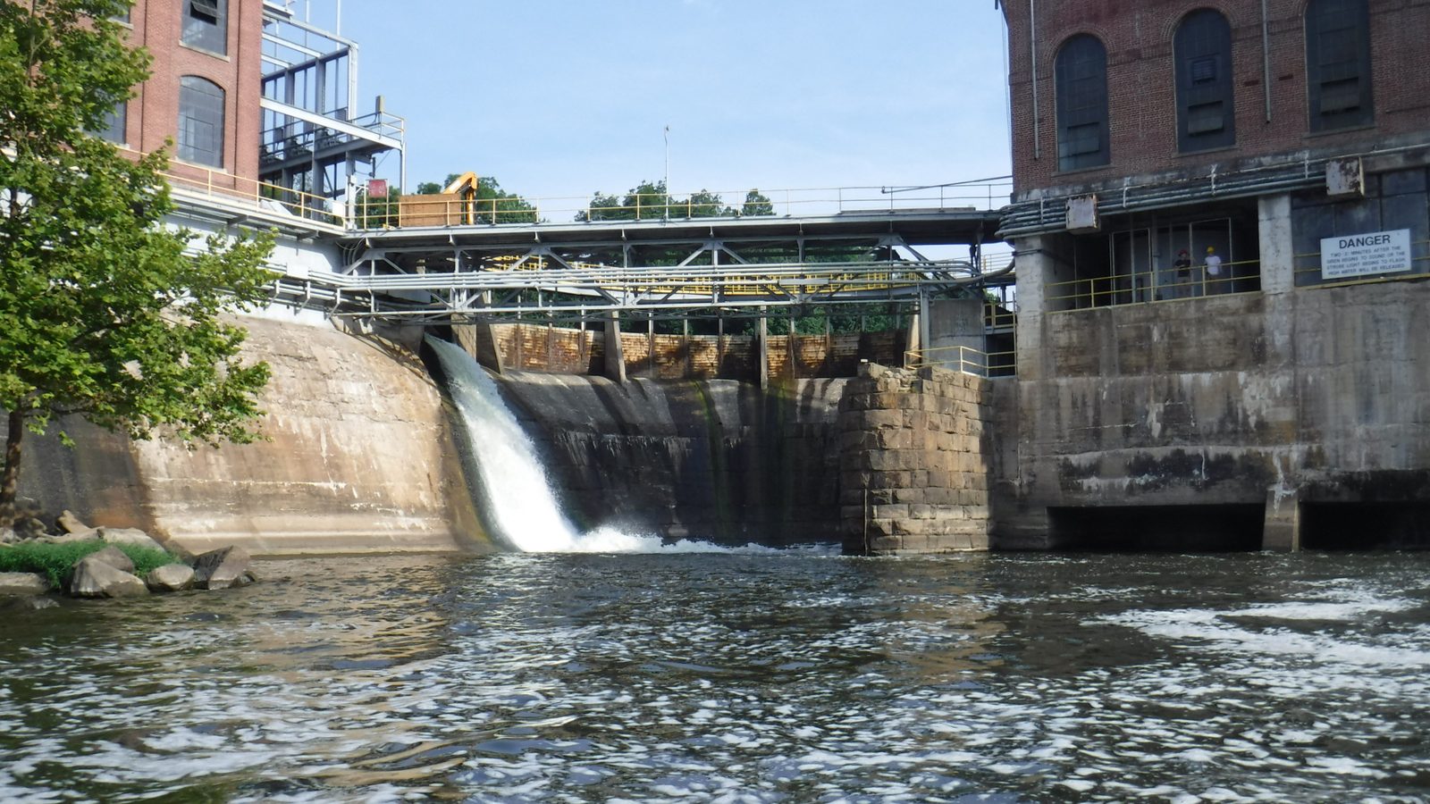 Spillway and brick powerhouse at a hydroelectric dam.