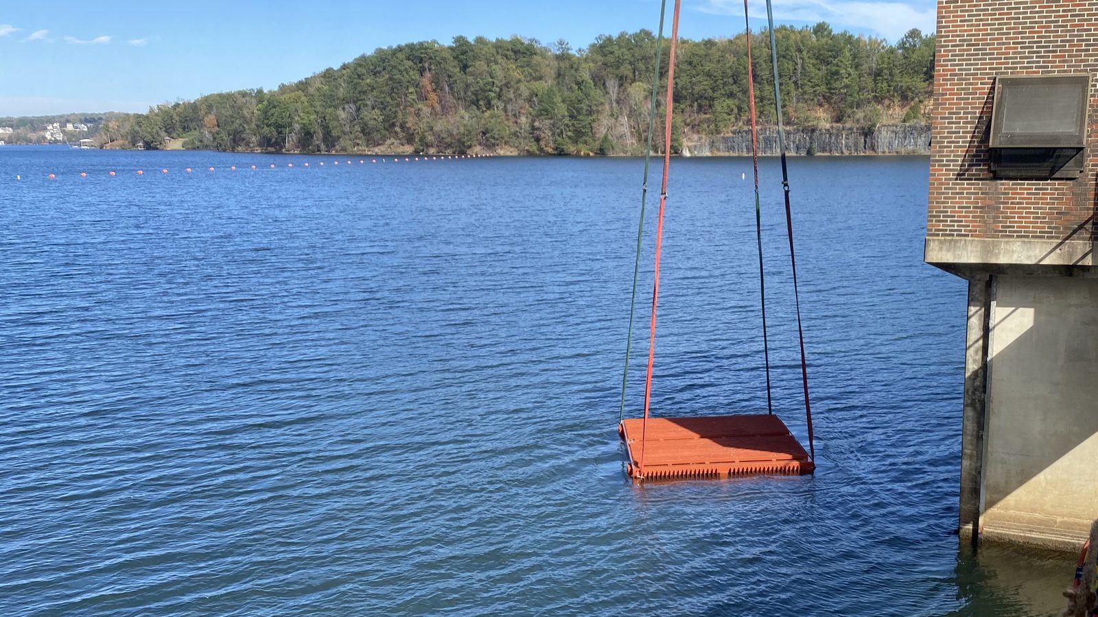 Intake rack lowered into a lake by crane.