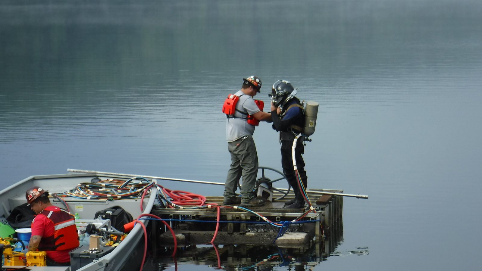 Diver and tender on a boat during a dam intake inspection.