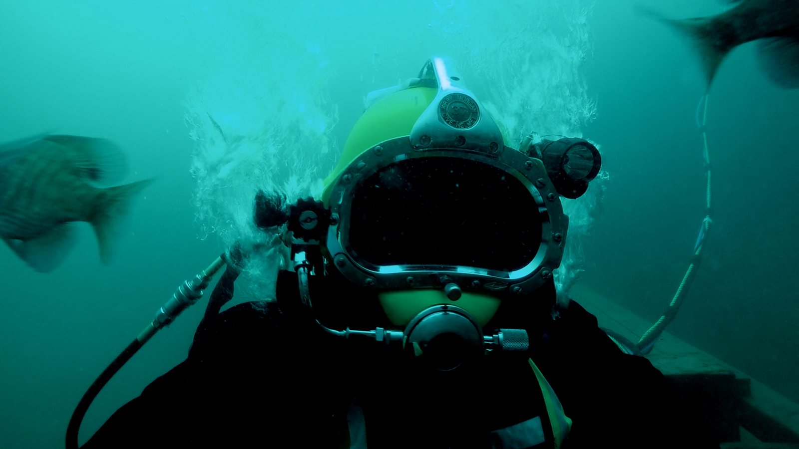 Commercial diver in a surface supplied helmet underwater.