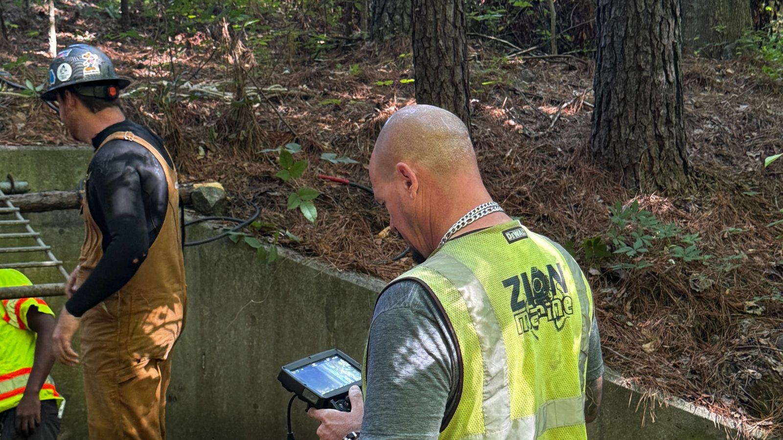 Crew inspecting a dam outlet with a crawler camera.