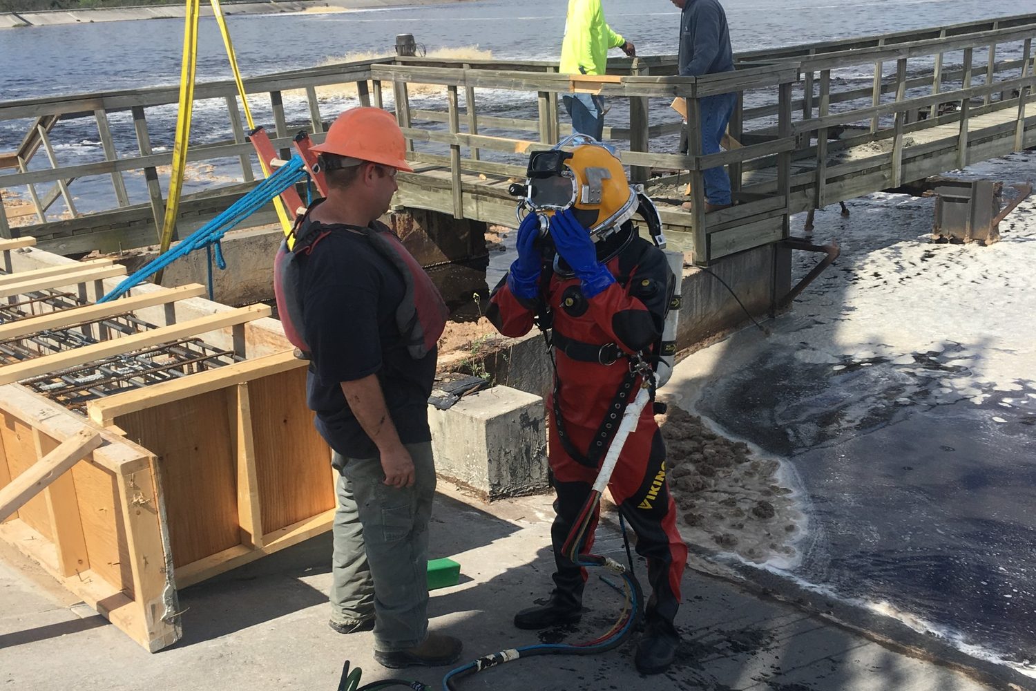 Diver putting on a helmet at a dam.