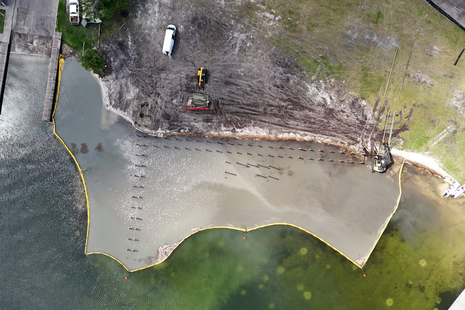 Aerial view of a silt curtain around a pier construction site on a lake.