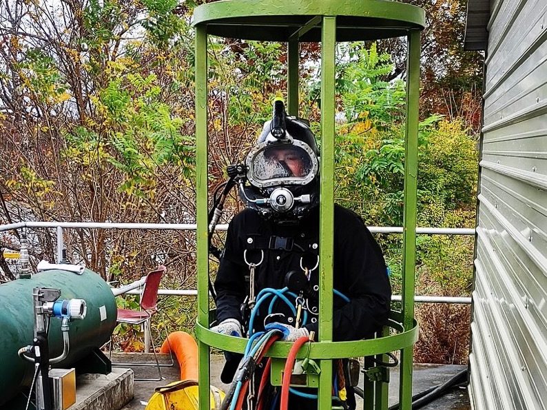 Diver in a green stage cage.