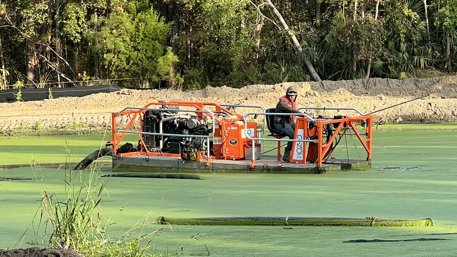 Dredge working in a green pond at a water intake.