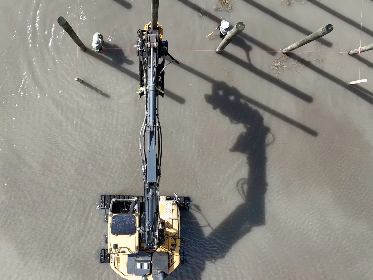 Aerial view of marine construction crew driving timber piles and building a new municipal waterfront pier on Lake Fairview.