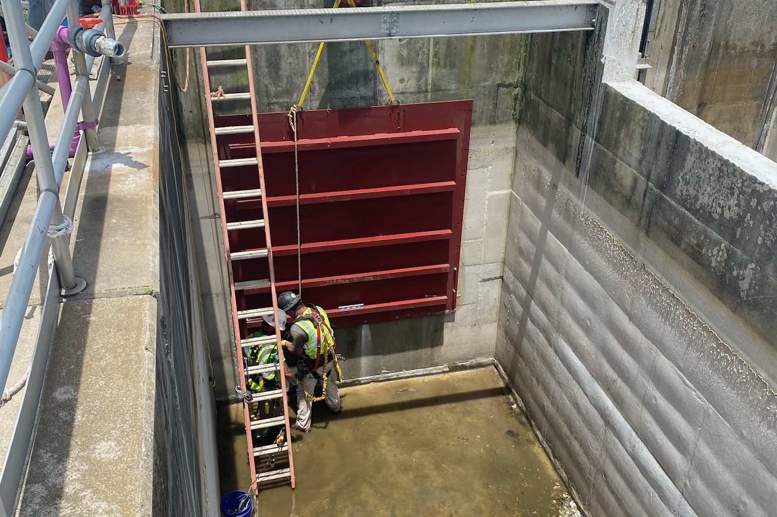 Slide gate lowered into a plant channel with the crew below.