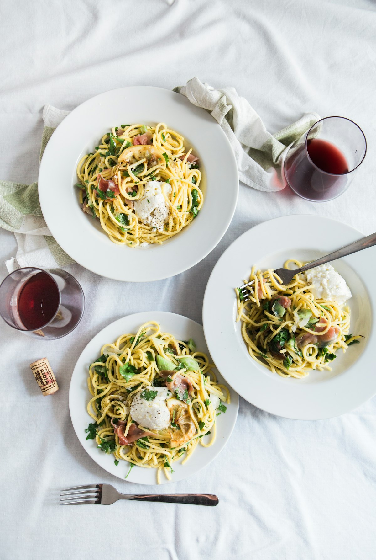 A table with pasta, pizza and a glass of wine