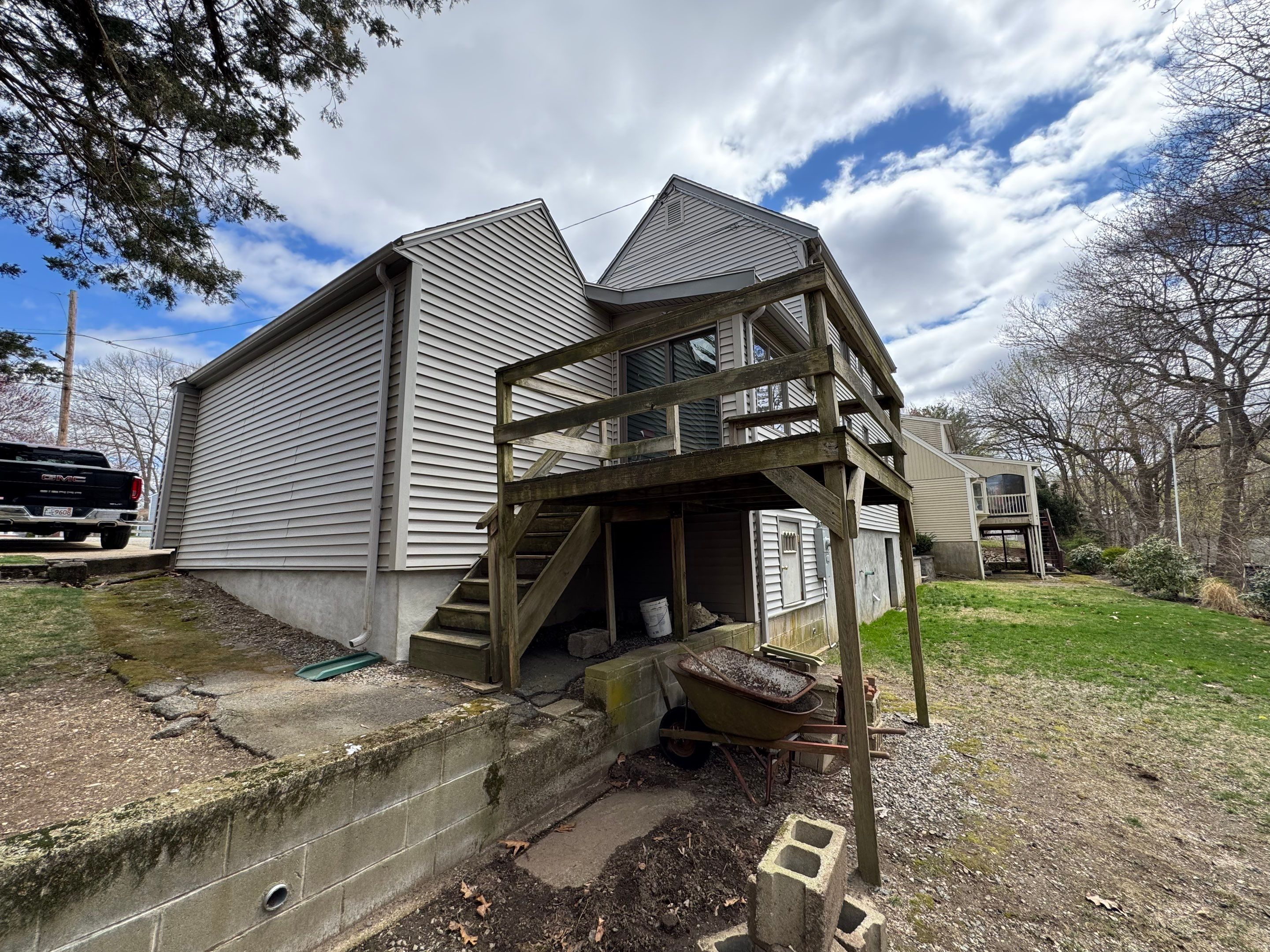 Before build: weathered, unfinished raised wood deck and steep outdoor stairs on a Massachusetts home