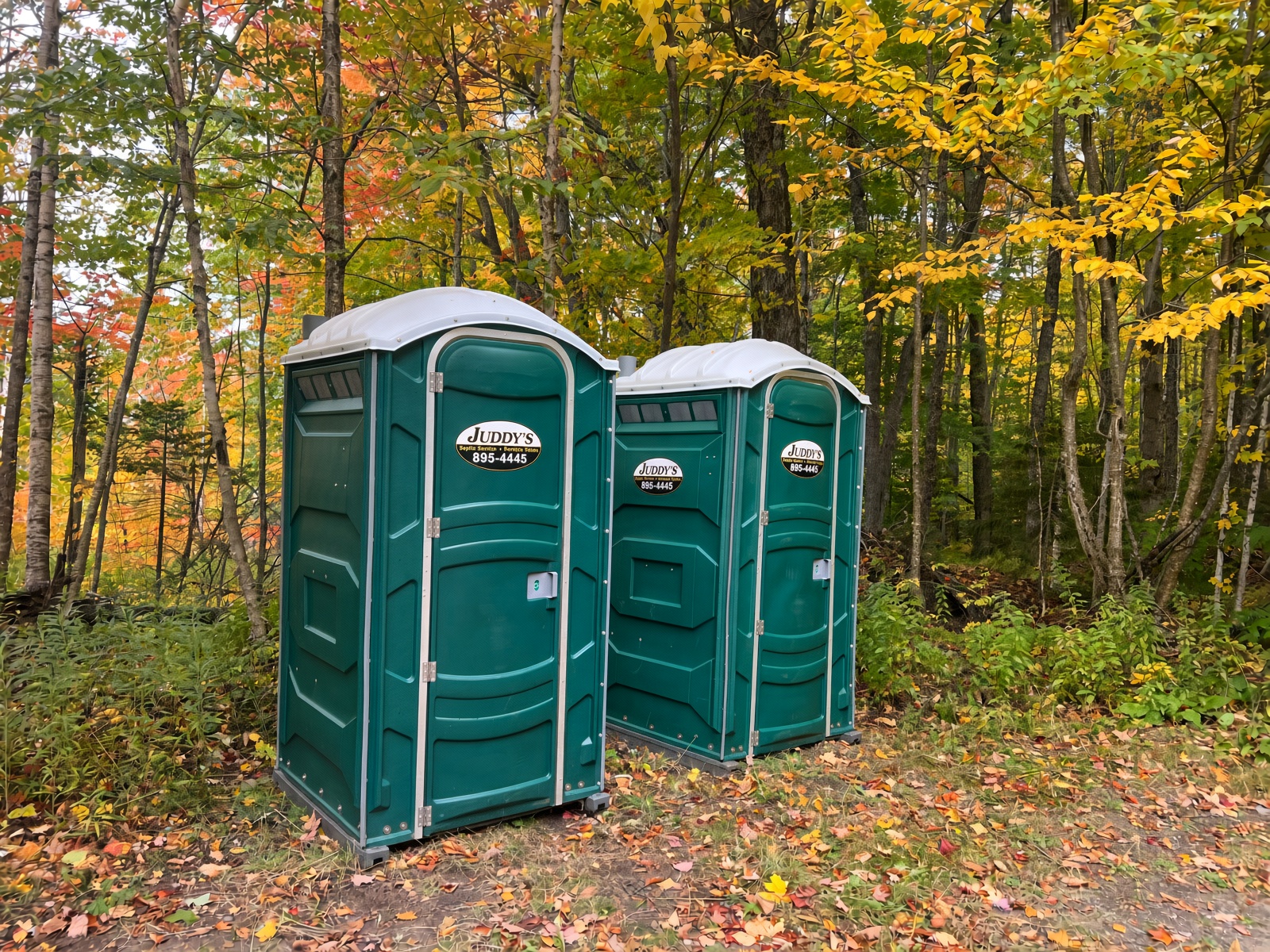 Juddy's portable toilets placed outdoors in a wooded Vermont setting