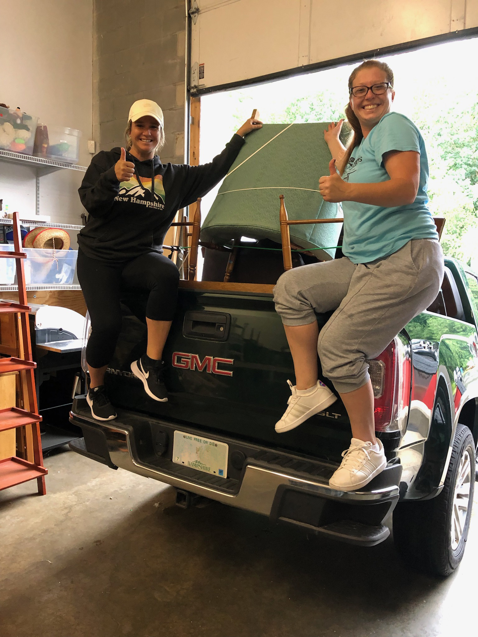 Volunteers smiling in a truck loaded with furniture for delivery to veterans