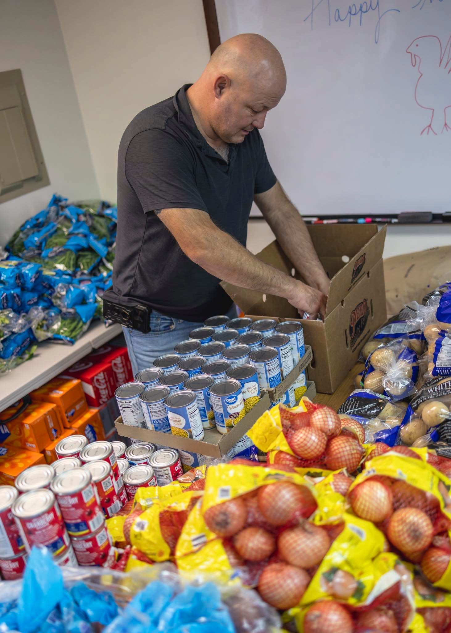 Volunteer sorting canned goods and vegetables for Thanksgiving meal boxes