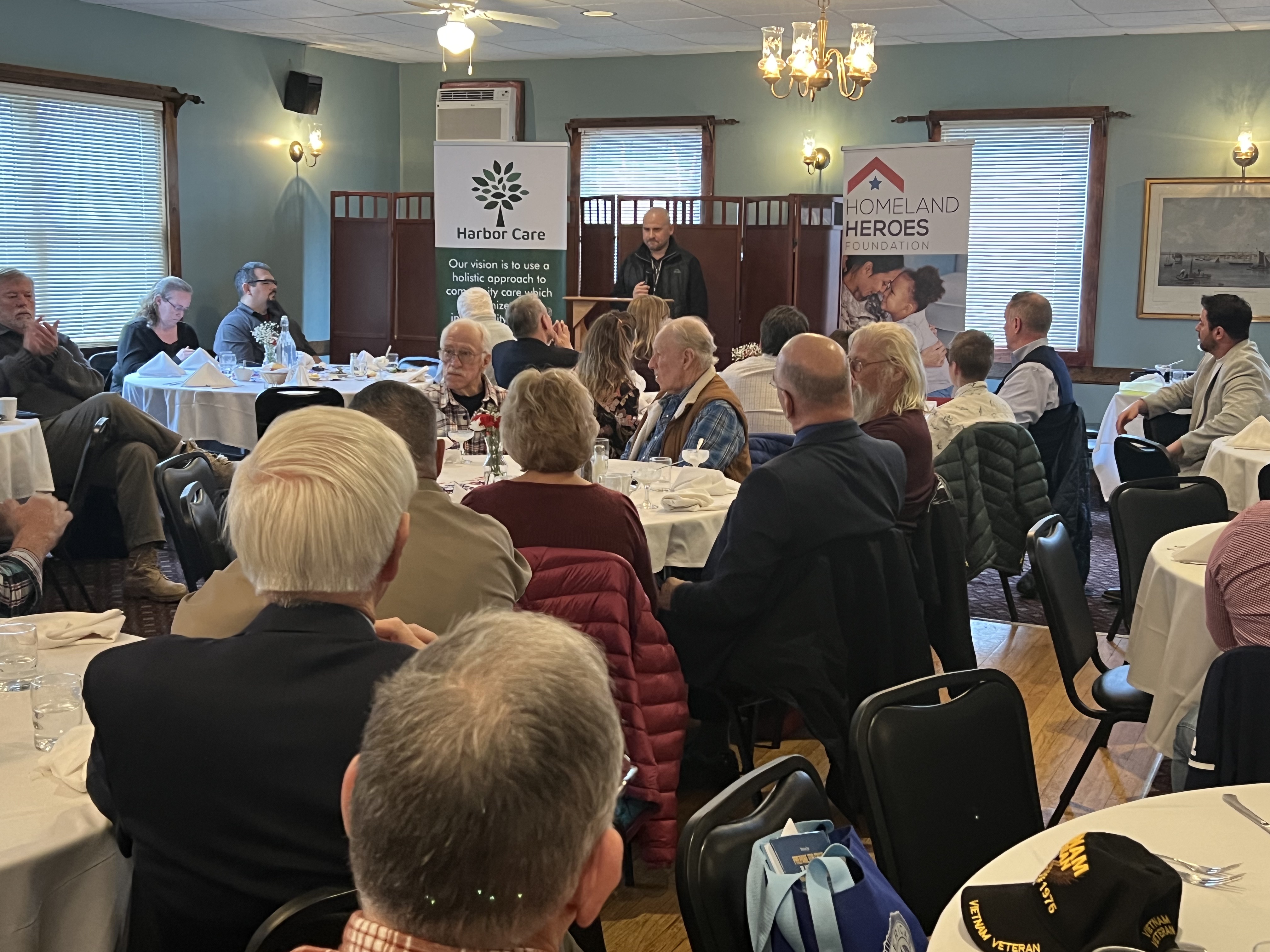 Veterans Day luncheon attendees gathered at tables with Homeland Heroes Foundation banner