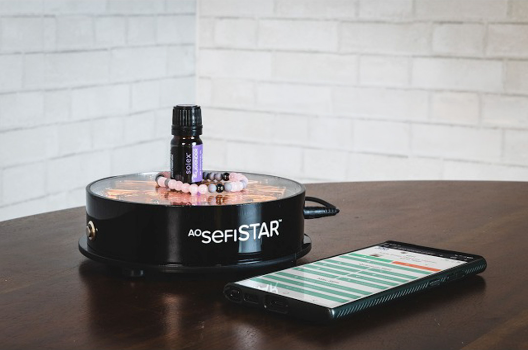 AO SefiSTAR unit with essential oil and bracelet beside a smartphone