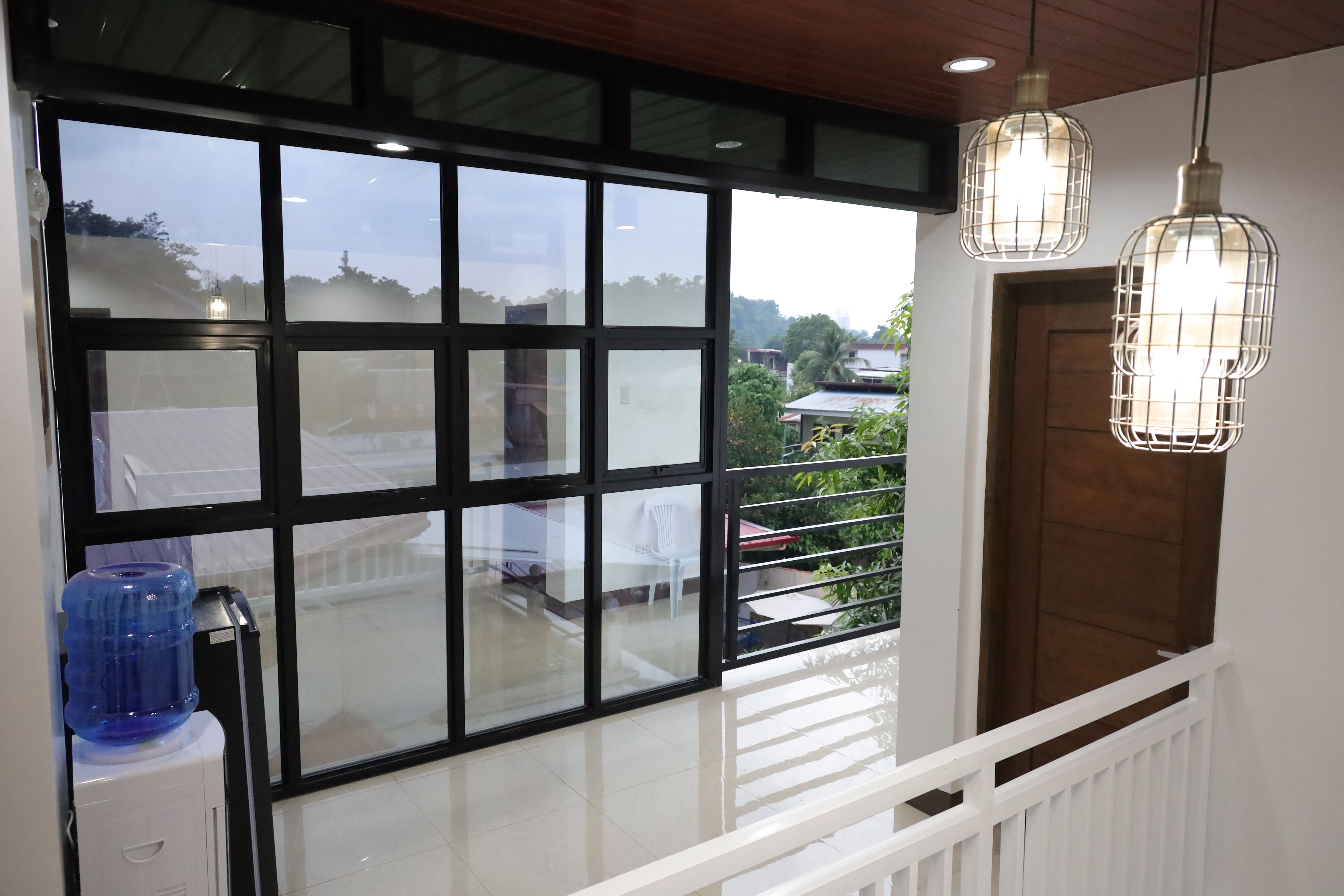 Bright 2nd floor hallway with large grid glass windows, pendant lanterns, and water dispenser