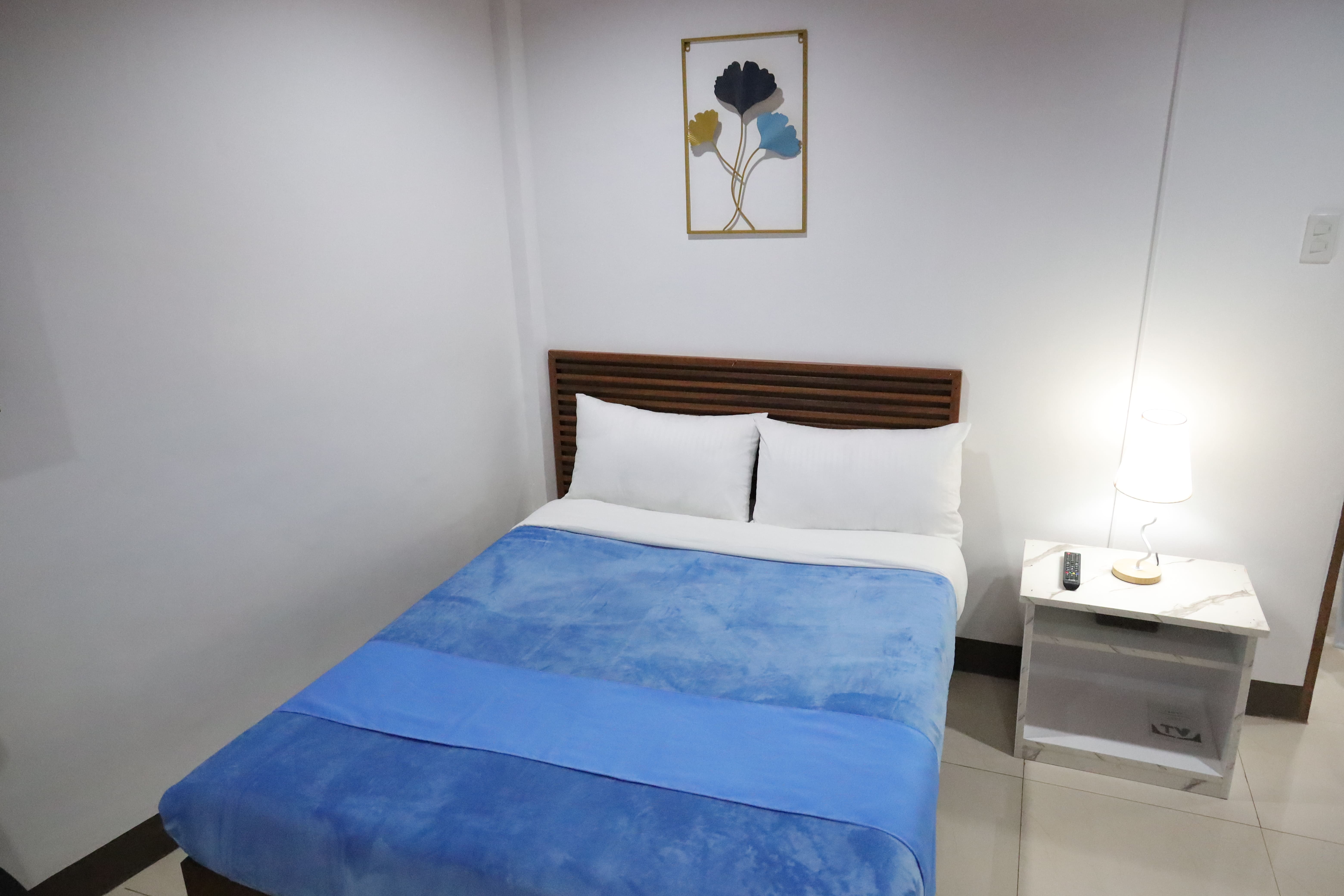 Cozy bed with slatted wood headboard, blue blanket, and warm bedside lighting