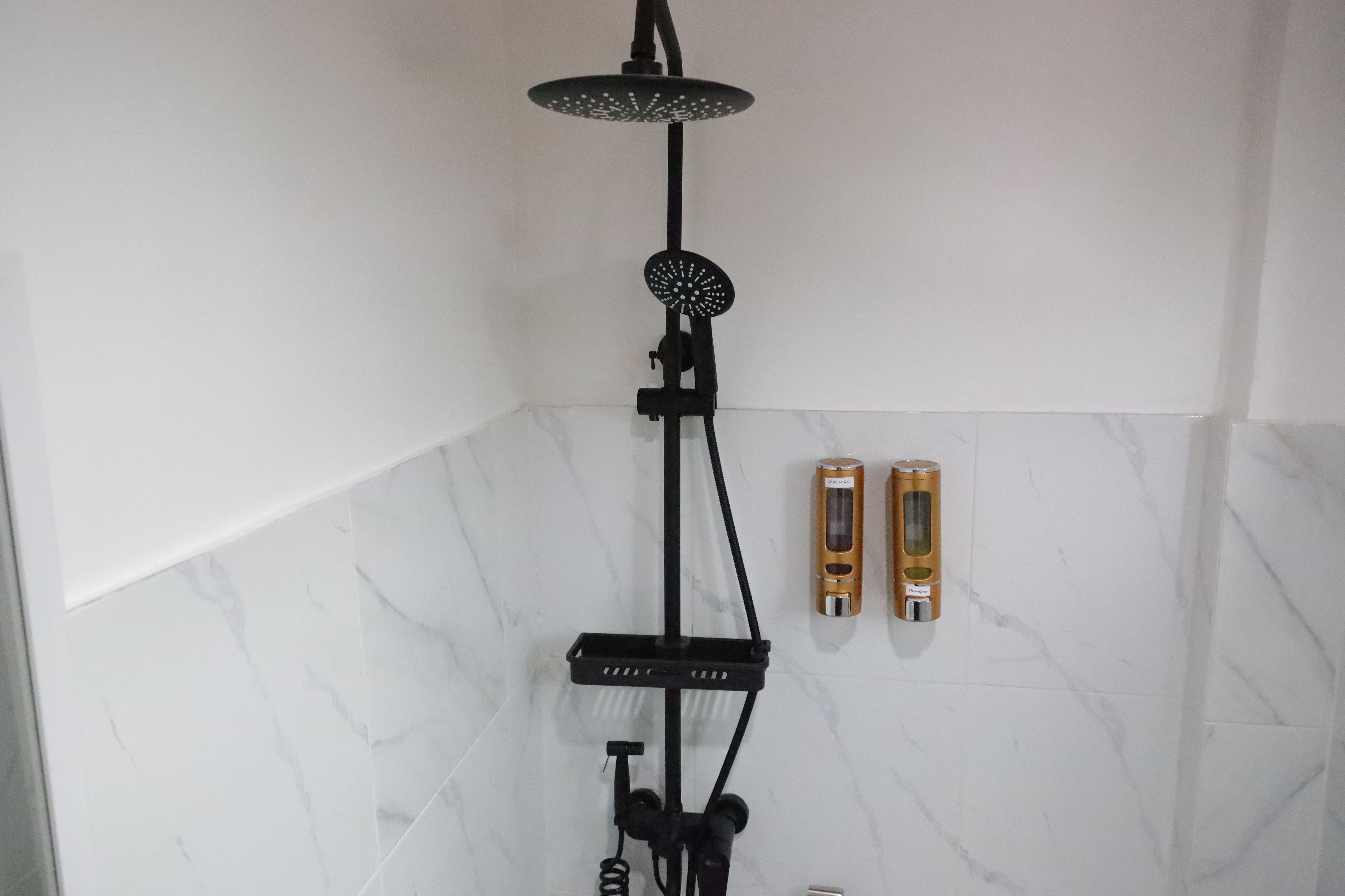 Matte black rainfall shower head, hand sprayer, and wall-mounted bath essentials dispensers