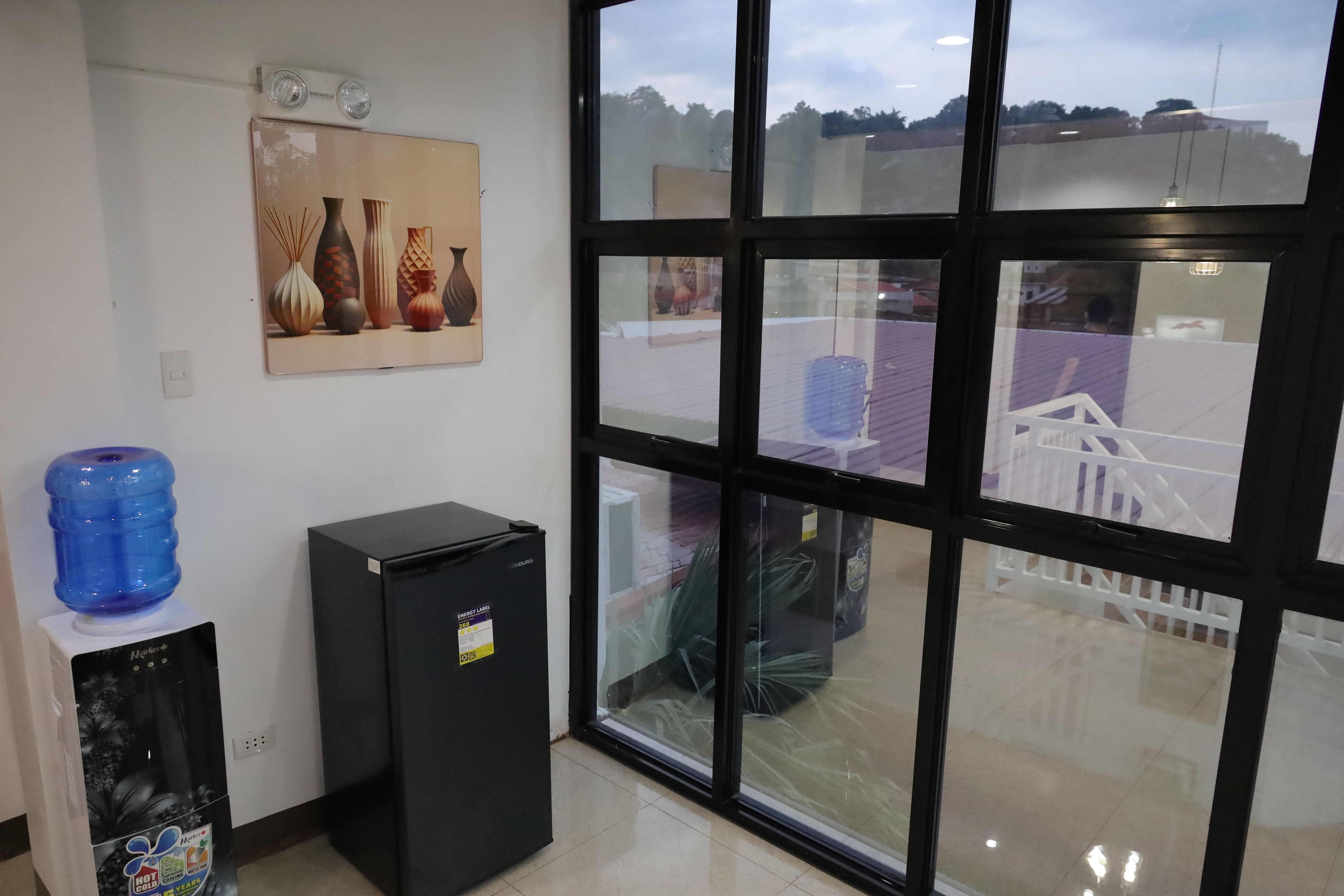 Common area guest water station with mini-fridge and modern wall artwork