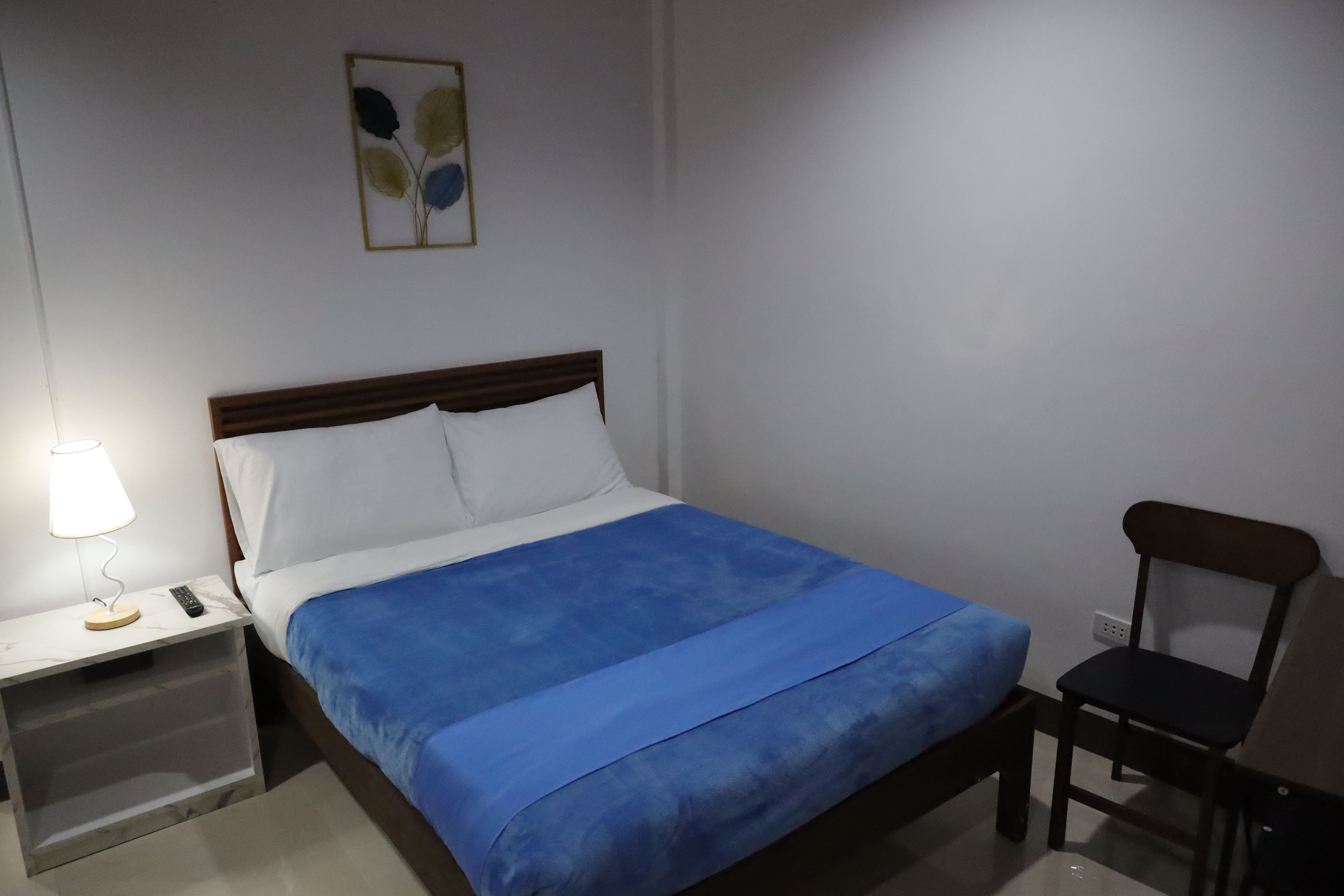 Cozy guest room with plush wooden double bed, warm bedside lamp, and wall art