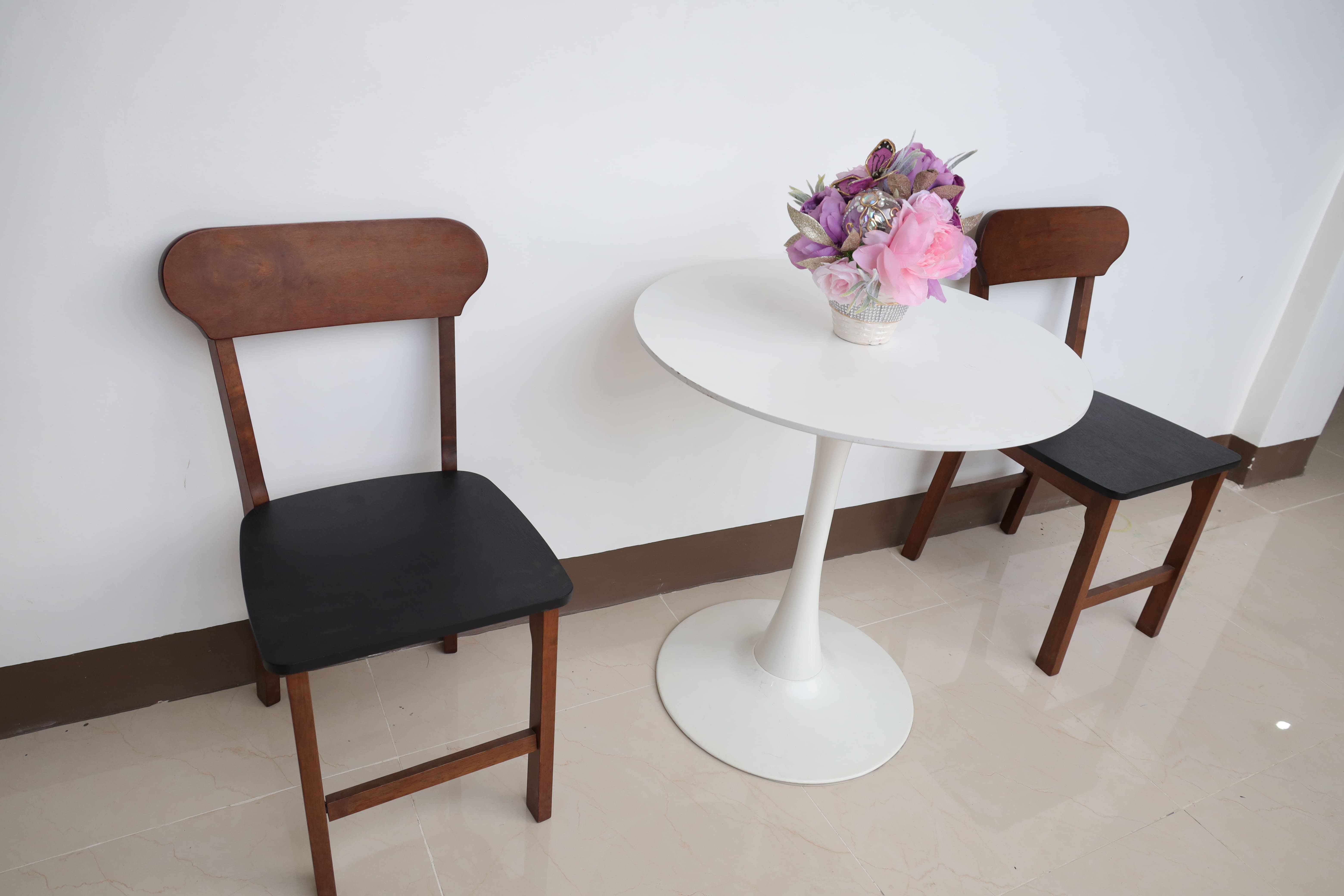 Intimate guest seating corner with wooden chairs and floral vase centerpiece