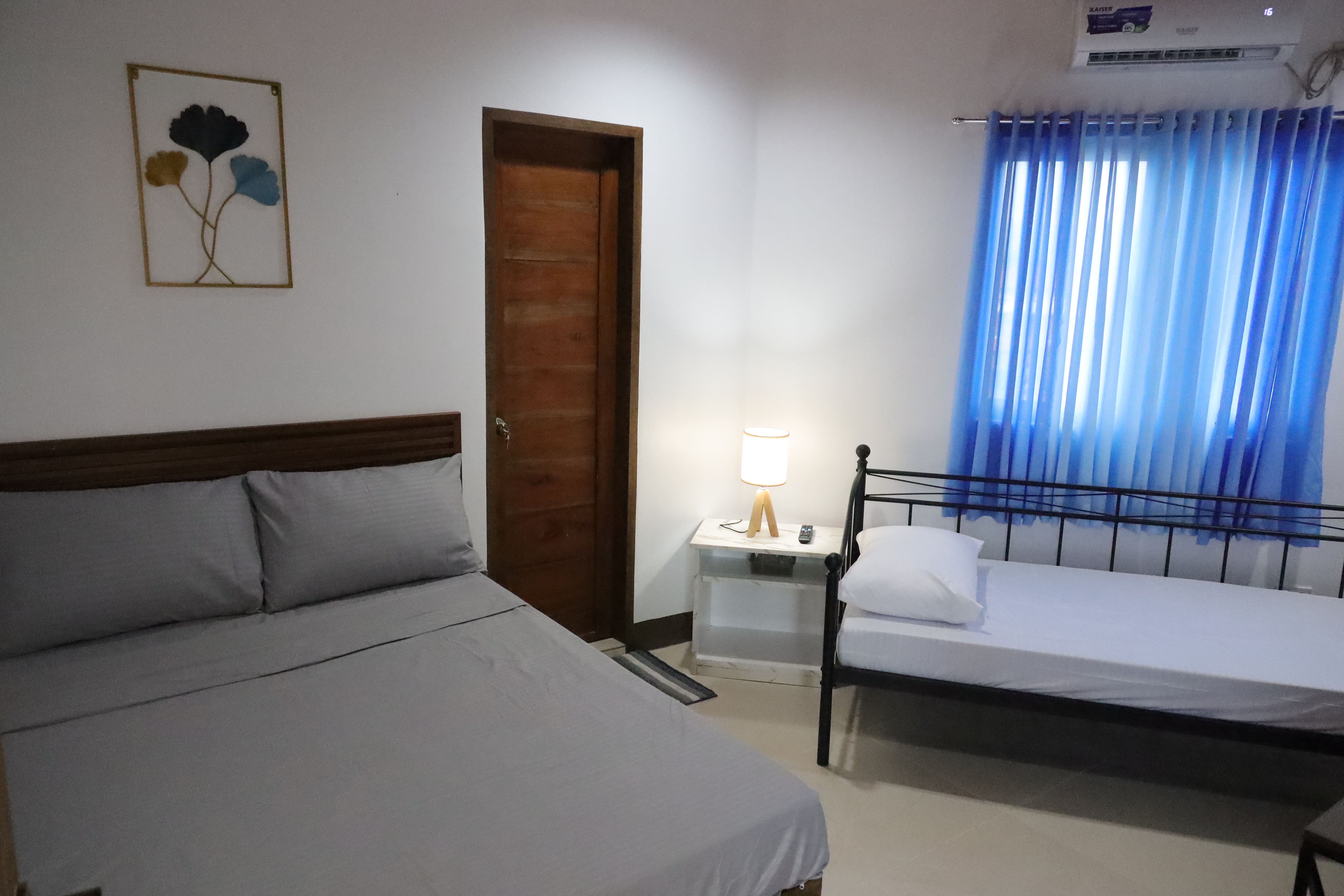 Double room setup with double bed, single daybed, bedside lamp, and air conditioning