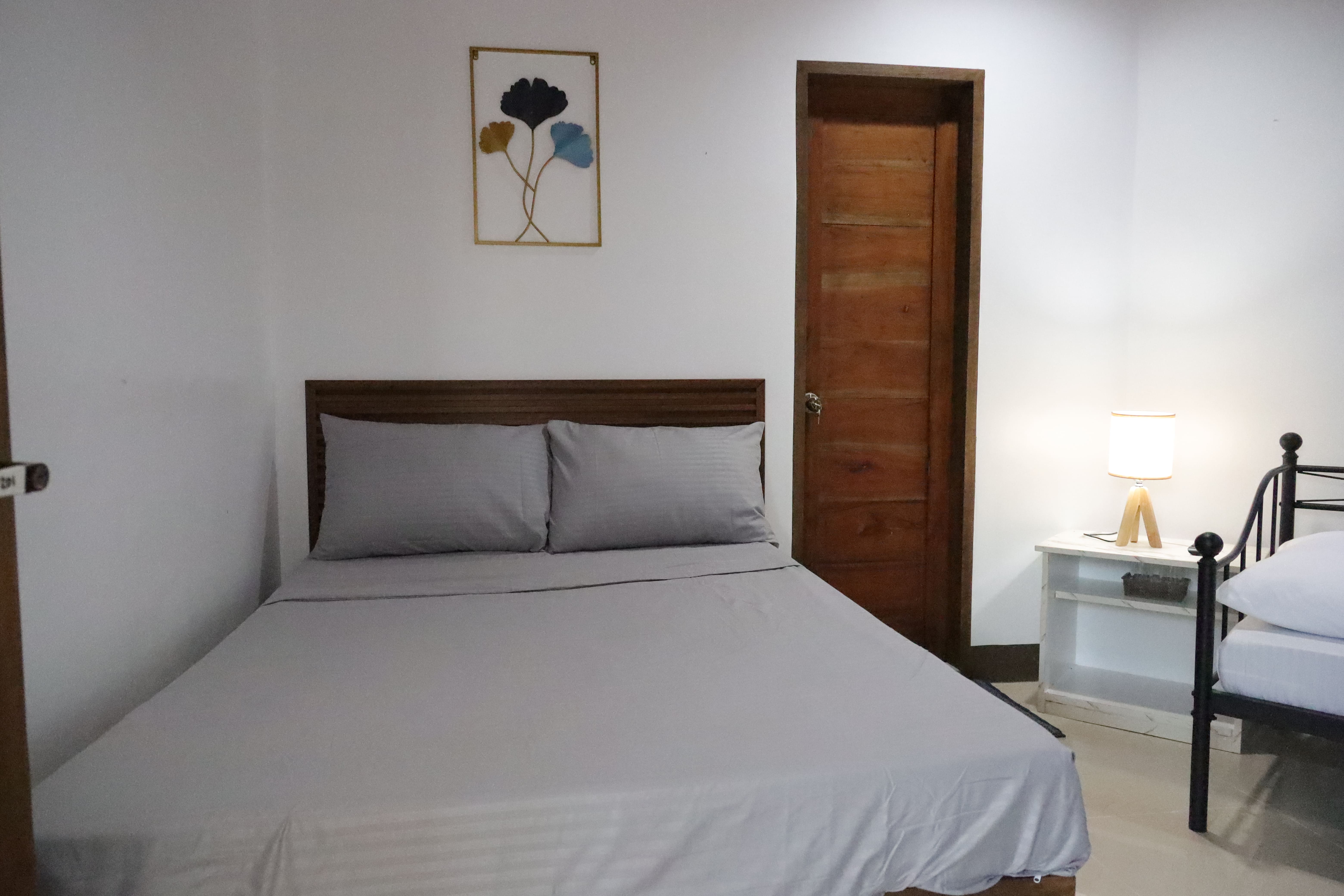 Plush wood-framed double bed with bedside lamp and botanical wall art
