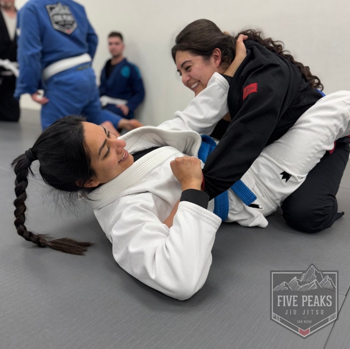 Two smiling female jiu jitsu students training technique on the mats at Five Peaks Jiu Jitsu
