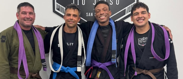 Five Peaks adult students and coaches smiling together in gis and belt promotions