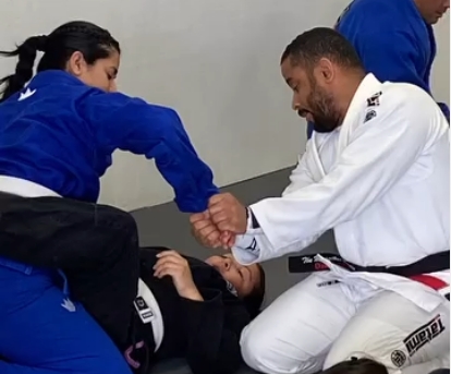 Black belt instructor teaching arm technique to adult female student during private lesson at Five Peaks Jiu Jitsu