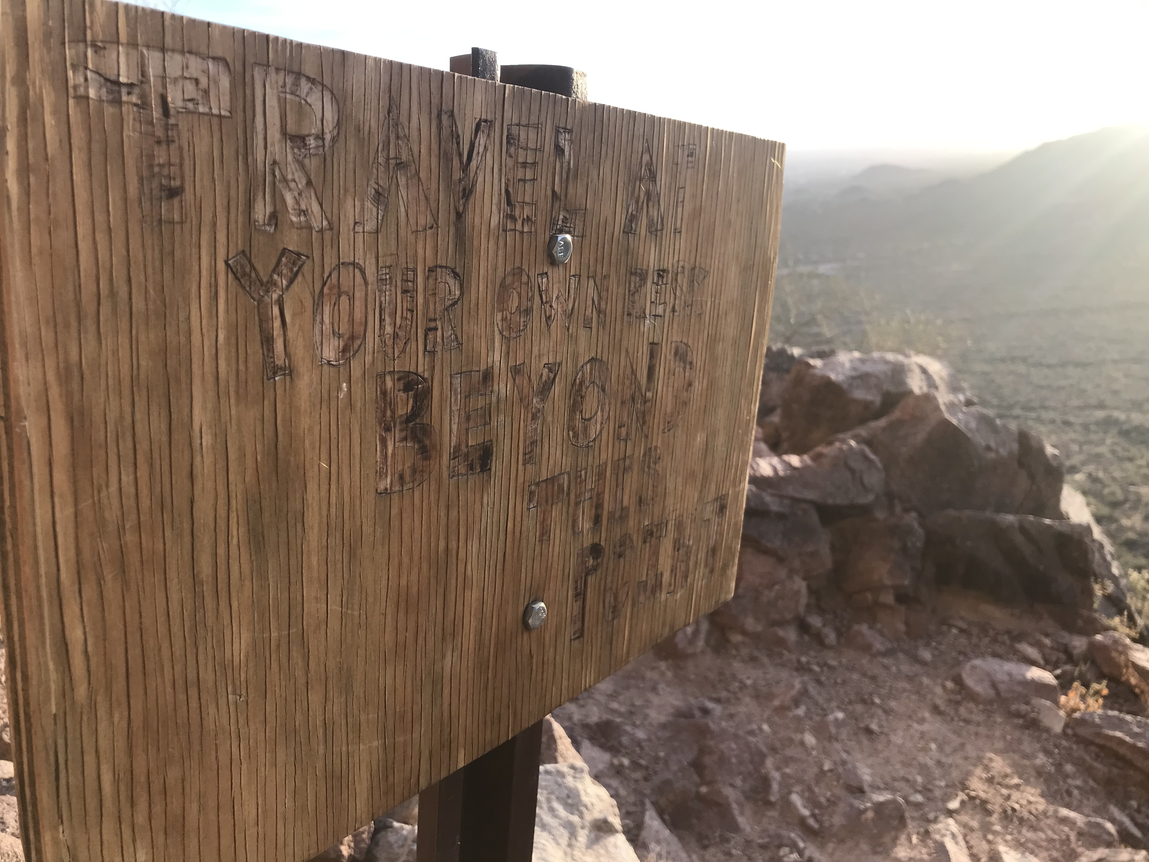 Summit marker in rugged desert terrain where protective handwear meets the environment.