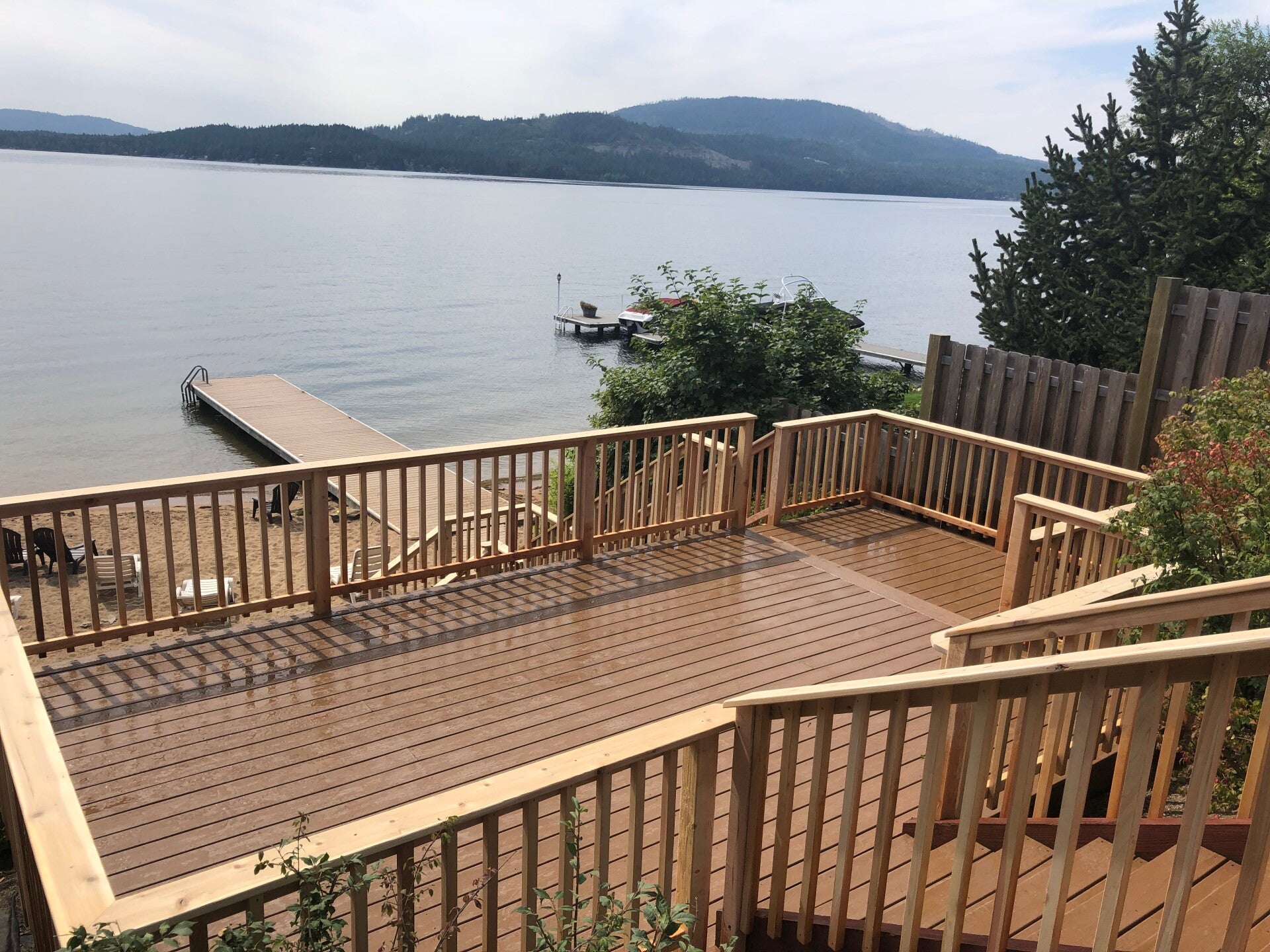 Lakefront deck with wood railings and stairs overlooking the water and a dock