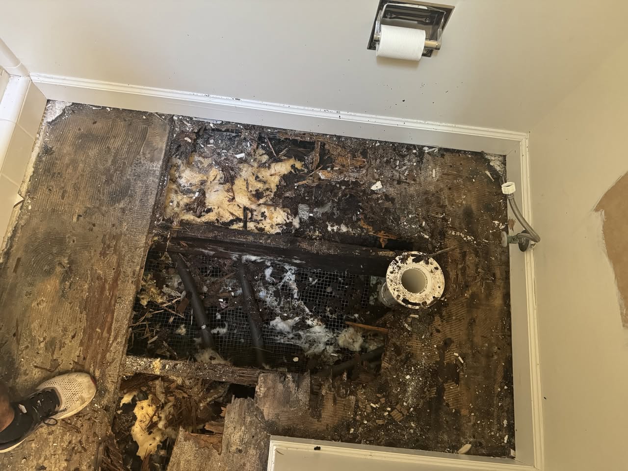 Rotted, water-damaged bathroom floor and subfloor exposed during removal, with deteriorated wood visible.