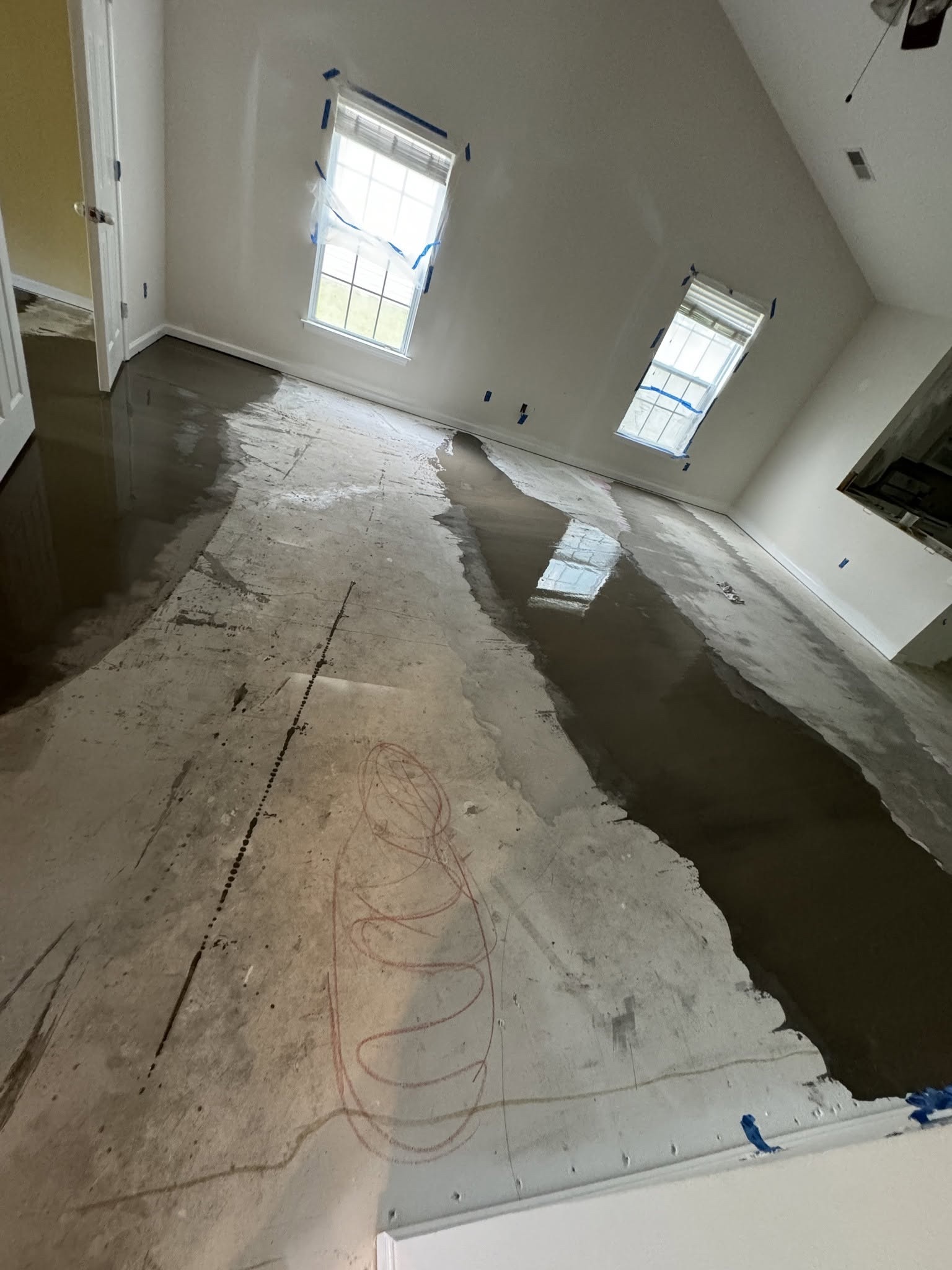 Subfloor leveling compound poured and spread across uneven concrete substrate.