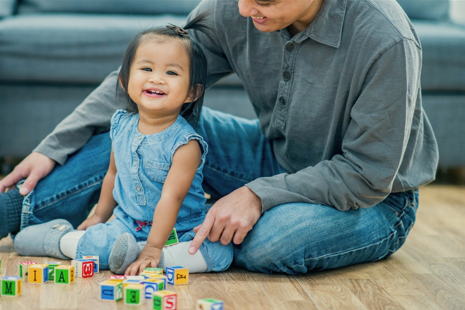 Dad playing blocks with his baby daughter on the living room floor