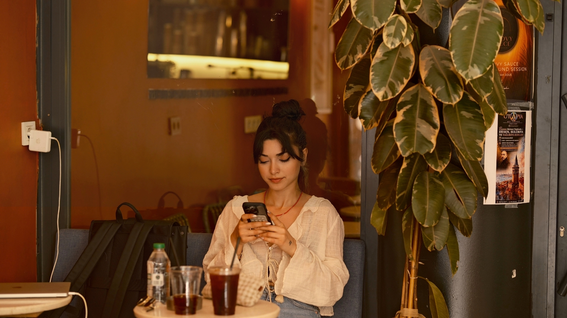 Woman relaxing with her phone and an iced coffee in a cozy café