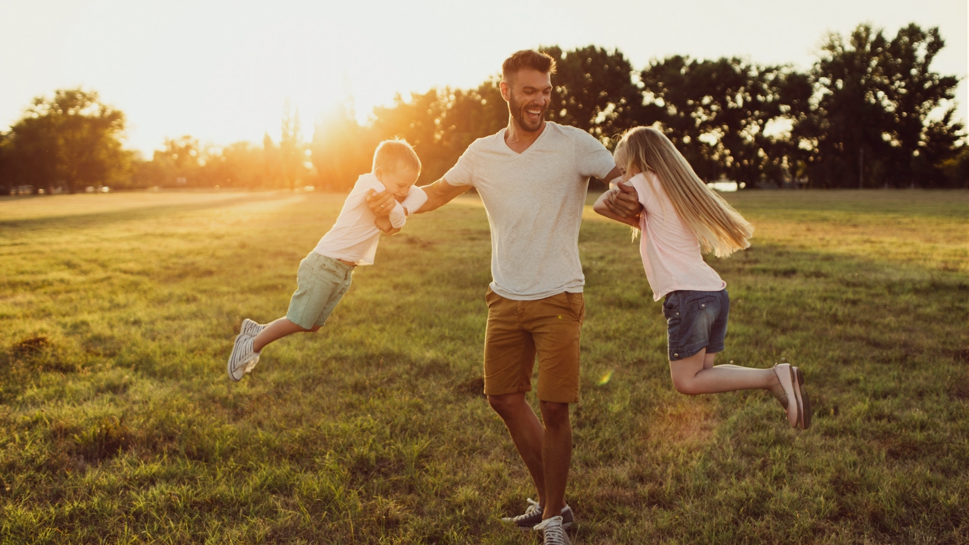 Dad playing with his kids outdoors at golden hour