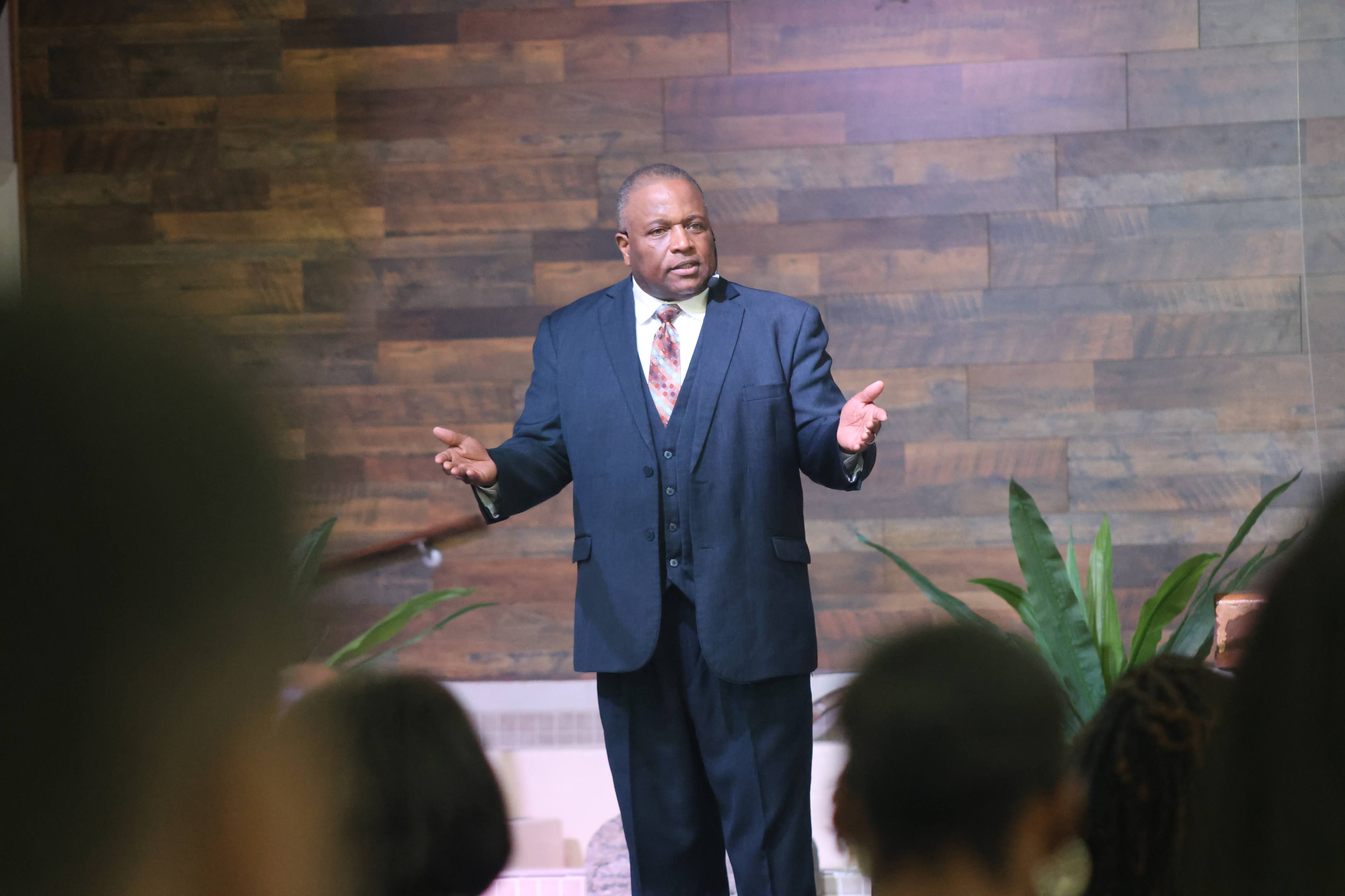 Alfred Johnson speaking with hands outstretched before a faith gathering