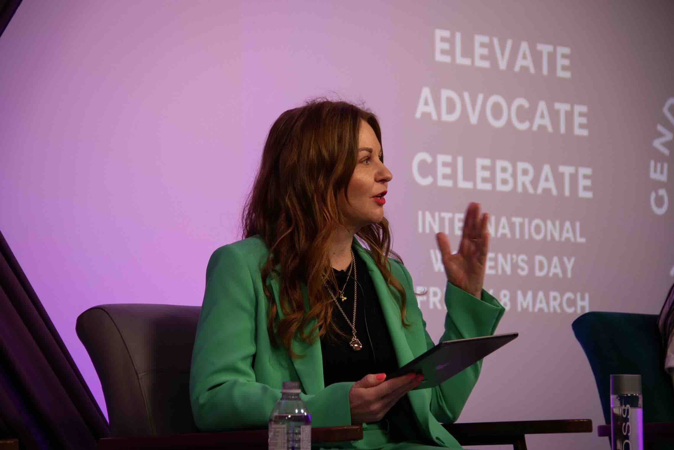 Rebecca Love speaking on stage — International Women's Day keynote