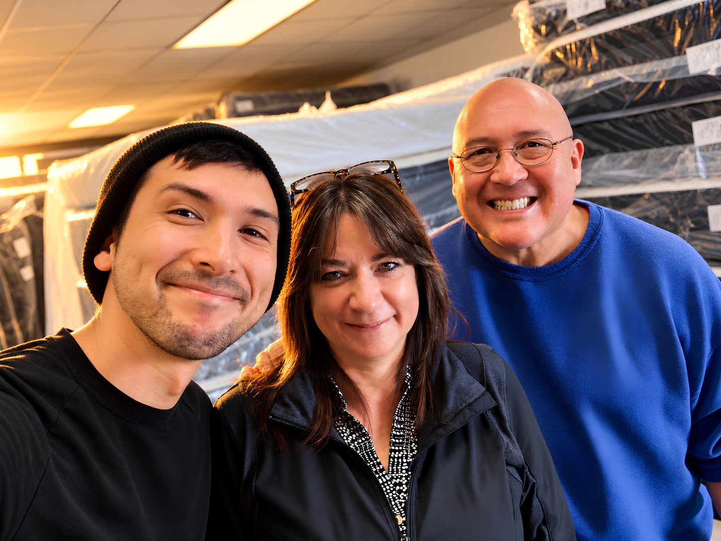 The family team at Lodi Mattress Direct in front of wrapped showroom mattresses
