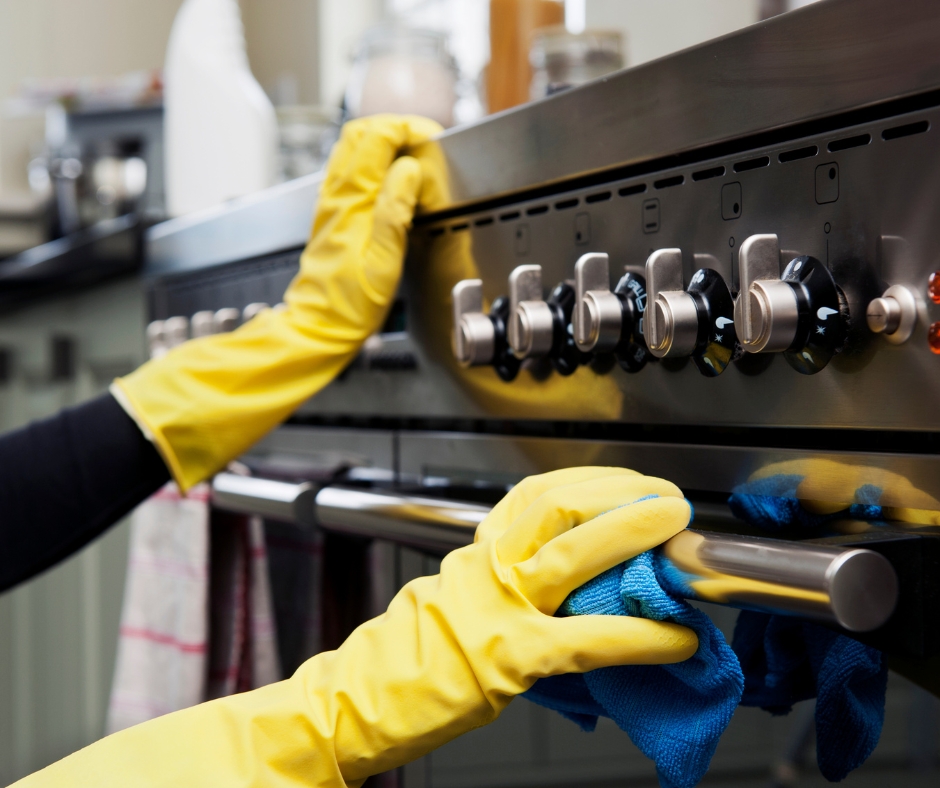 Deep cleaning oven range cooktop with microfiber cloth and protective yellow gloves