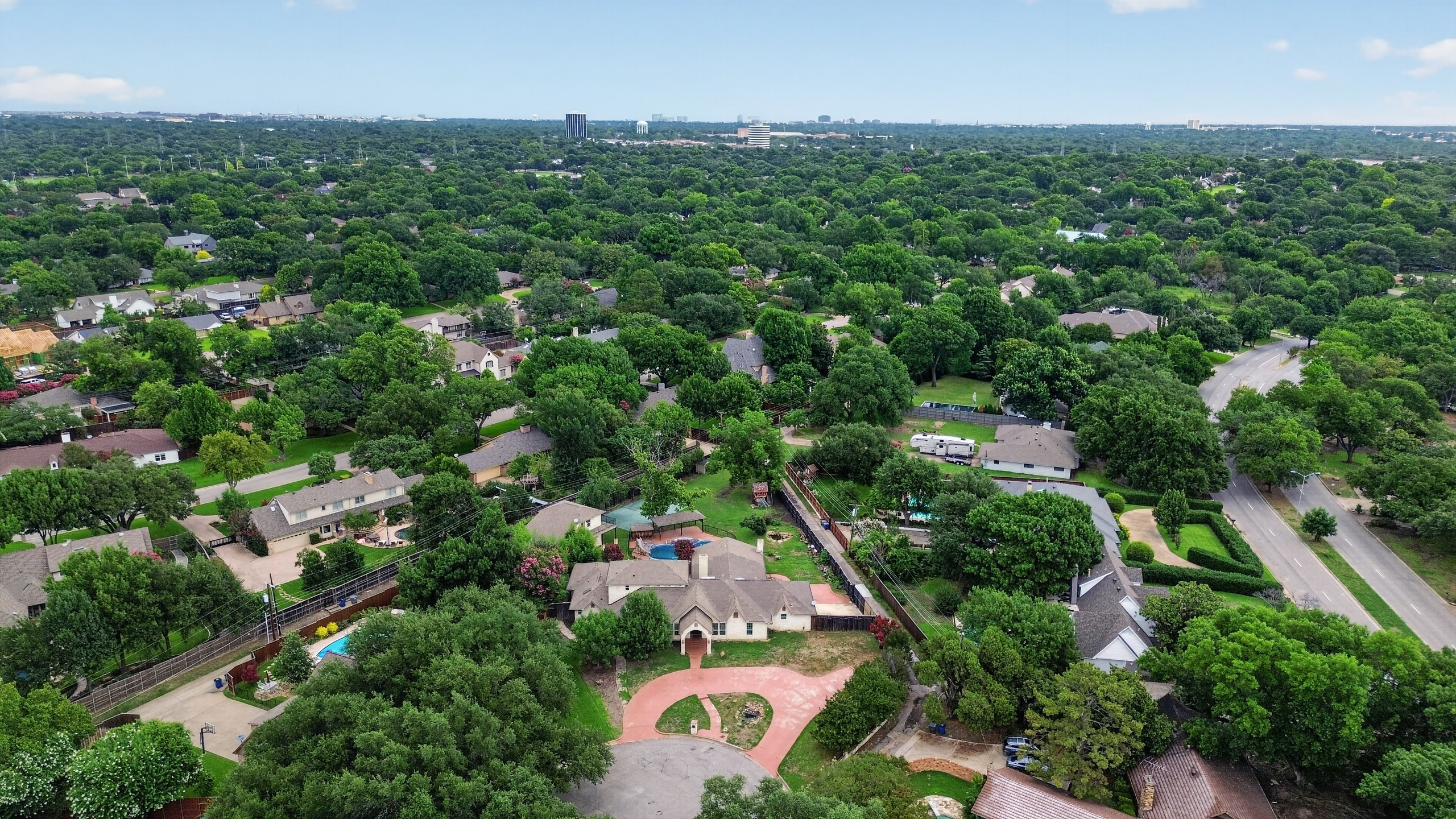 Mid-altitude aerial showing circular stamped drive, private courtyard, pool, and rear grounds