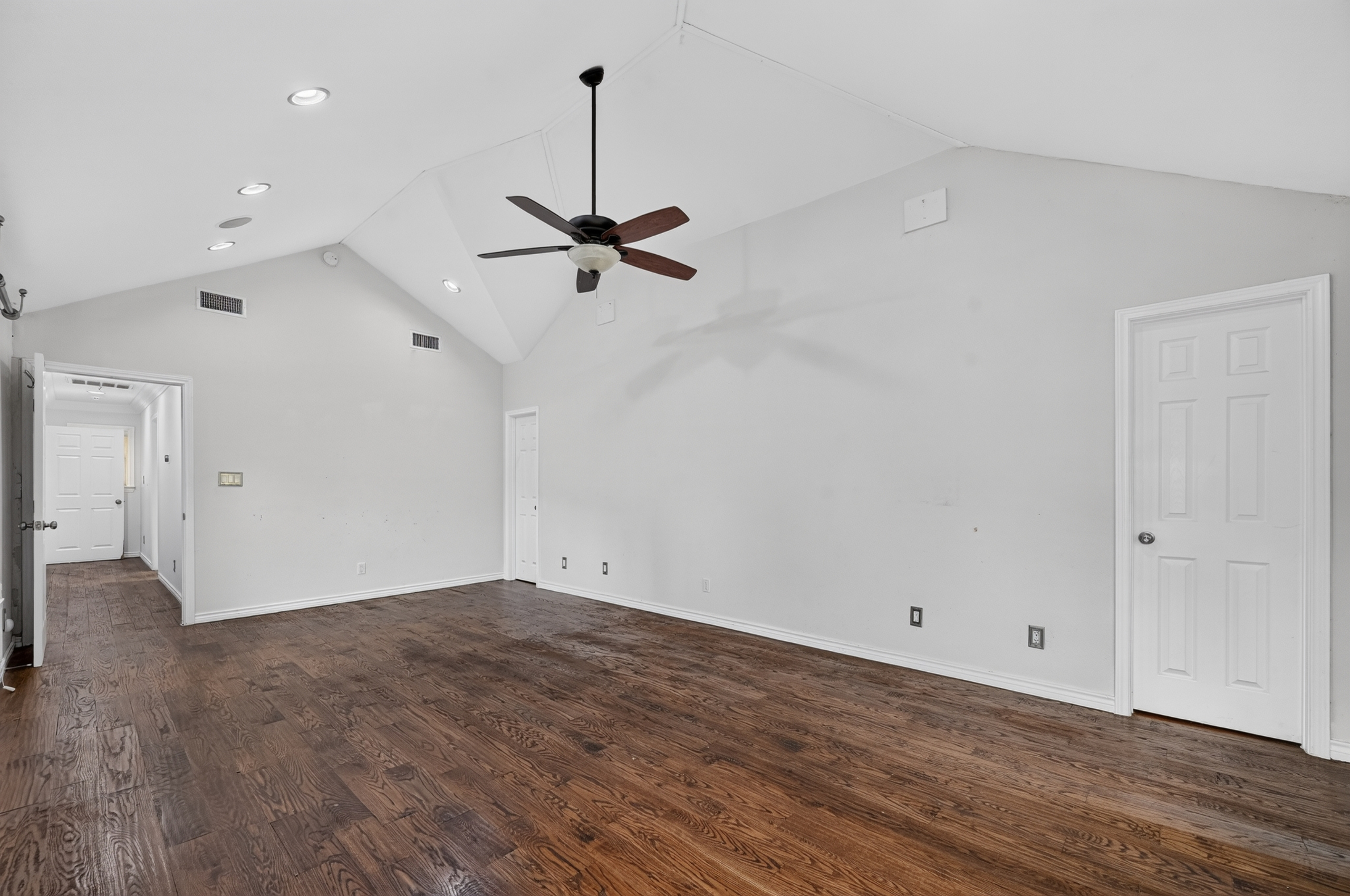 Vaulted ceiling bedroom with dark hardwood floors, recessed lighting, and designer ceiling fan